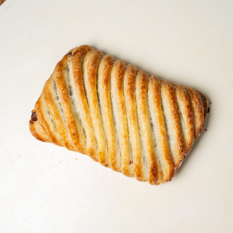 Golden-brown lattice-topped puff pastry turnover resting on a white plate.